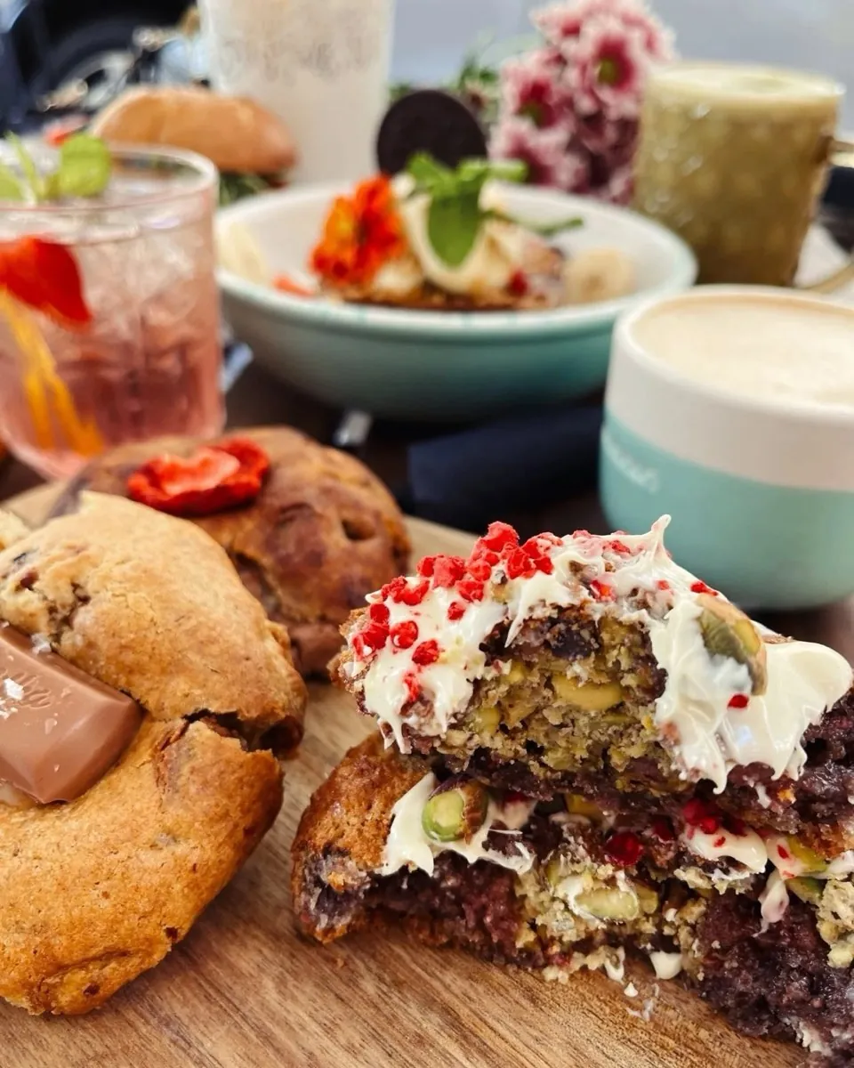 Sweet bakes with cream and freeze-dried berries beside a latte at Cookie Beacon